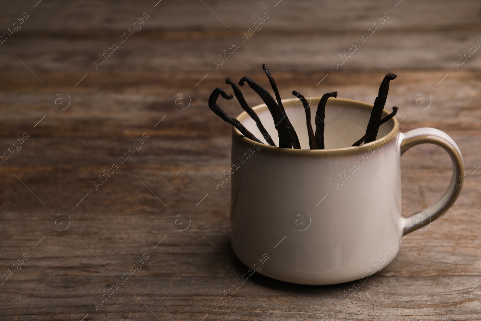 Photo of Vanilla sticks in cup on wooden table