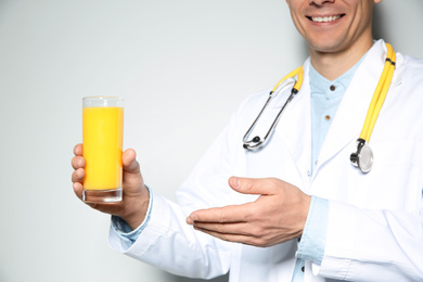 Photo of Nutritionist with glass of juice on light grey background, closeup