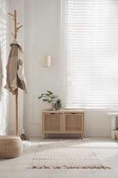 Stylish room interior with wooden chest of drawers and green plants