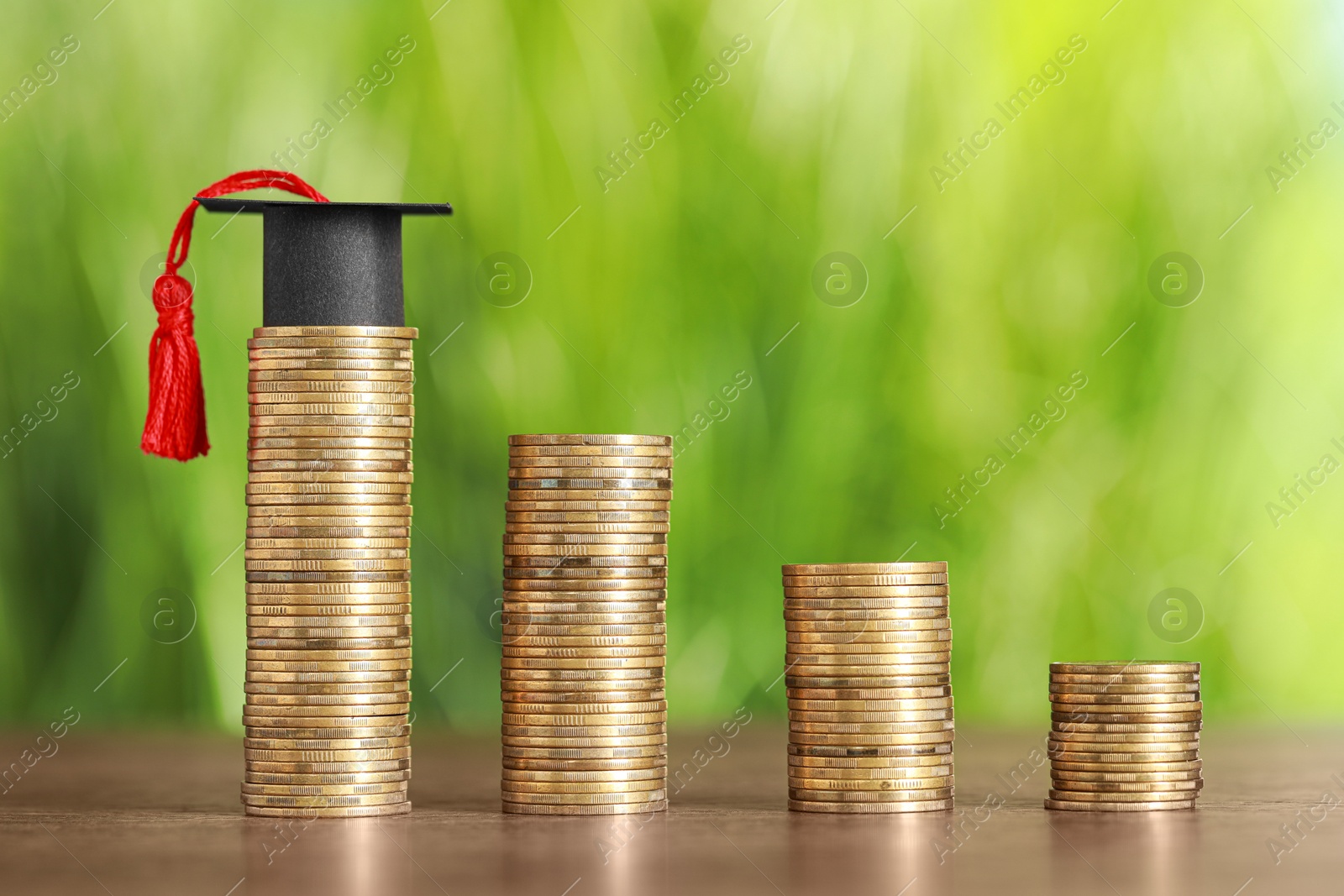 Photo of Scholarship concept. Coins and student graduation cap on wooden table