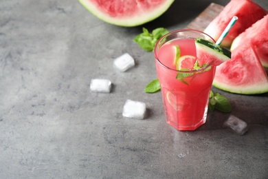 Photo of Glass of tasty refreshing drink with watermelon on grey table. Space for text