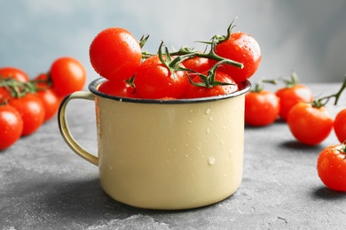 Photo of Metal mug with fresh ripe tomatoes on table