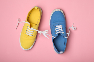 Shoes tied together on pink background, flat lay. April Fool's Day