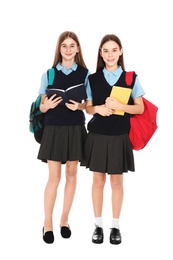 Photo of Full length portrait of teenage girls in school uniform with backpacks and books on white background