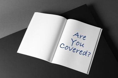 Image of Notebook with text ARE YOU COVERED? on dark background. Insurance concept