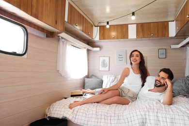 Photo of Happy young couple on bed in trailer, space for text. Camping vacation