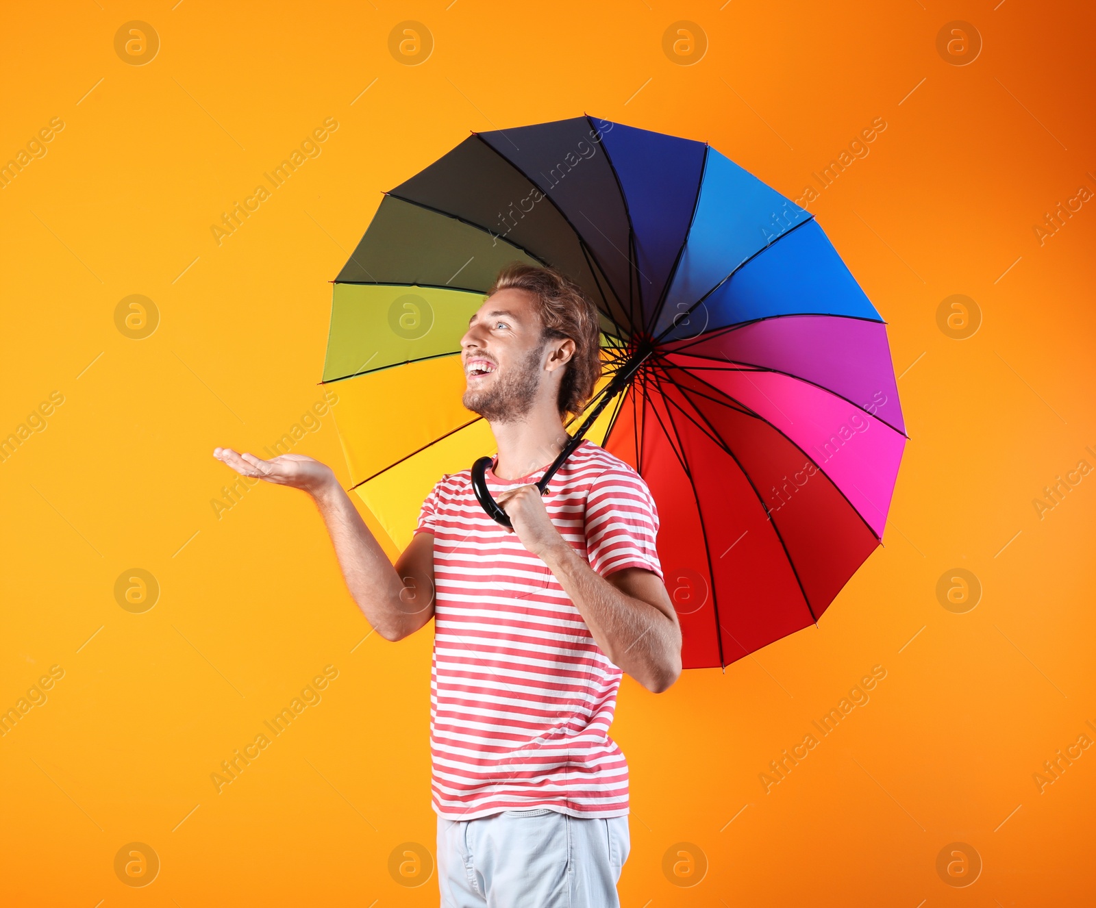 Photo of Man with rainbow umbrella on color background