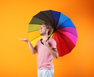 Man with rainbow umbrella on color background