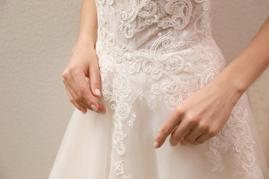 Photo of Woman trying on beautiful wedding dress indoors, closeup