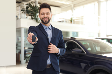 Salesman with key in modern car salon