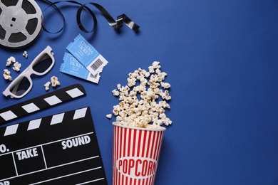 Photo of Flat lay composition with clapperboard, cinema tickets and 3d glasses on blue background, space for text