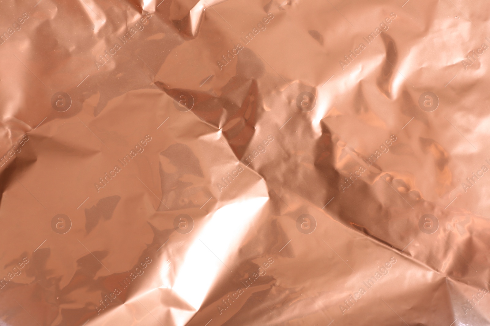Photo of Crumpled rose gold paper as background, closeup view