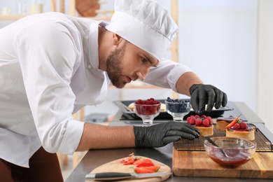 Male pastry chef preparing desserts at table in kitchen