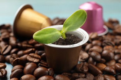 Photo of Coffee capsules with seedling and beans on table, closeup