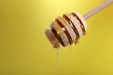 Photo of Delicious honey flowing down from dipper against golden background, closeup. Space for text