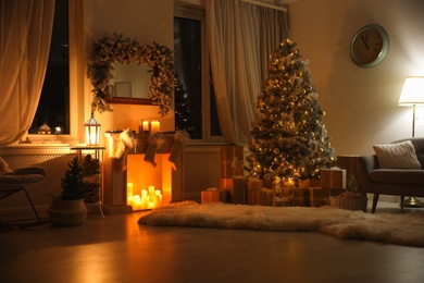 Photo of Stylish interior with beautiful Christmas tree and decorative fireplace at night