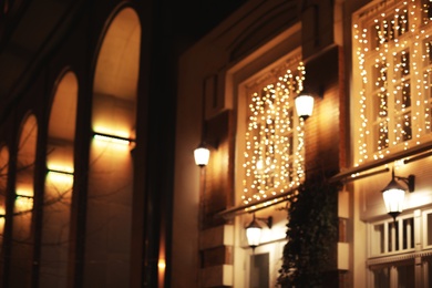 Blurred view of building with beautiful street lights at night. Bokeh effect