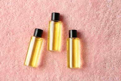 Mini bottles with cosmetic products on towel, flat lay. Hotel amenities