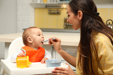 Young mother feeding her little baby at home