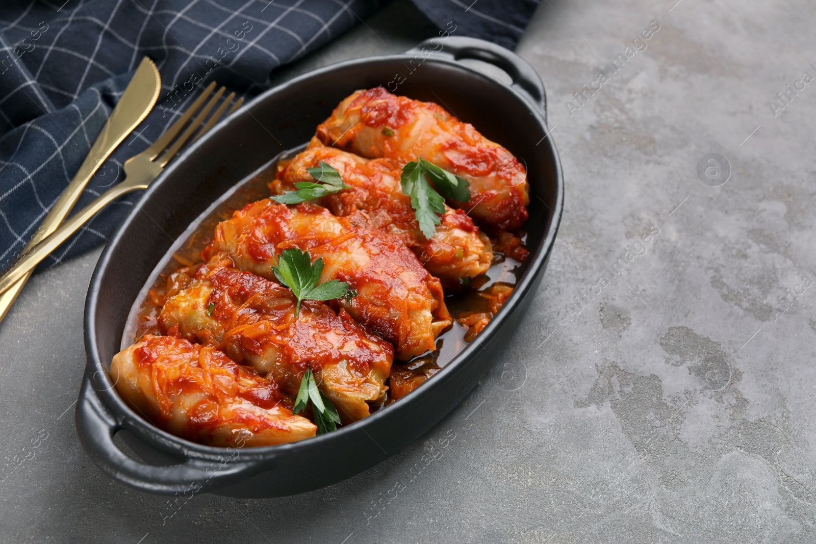 Photo of Delicious stuffed cabbage rolls cooked with tomato sauce on grey table, closeup. Space for text