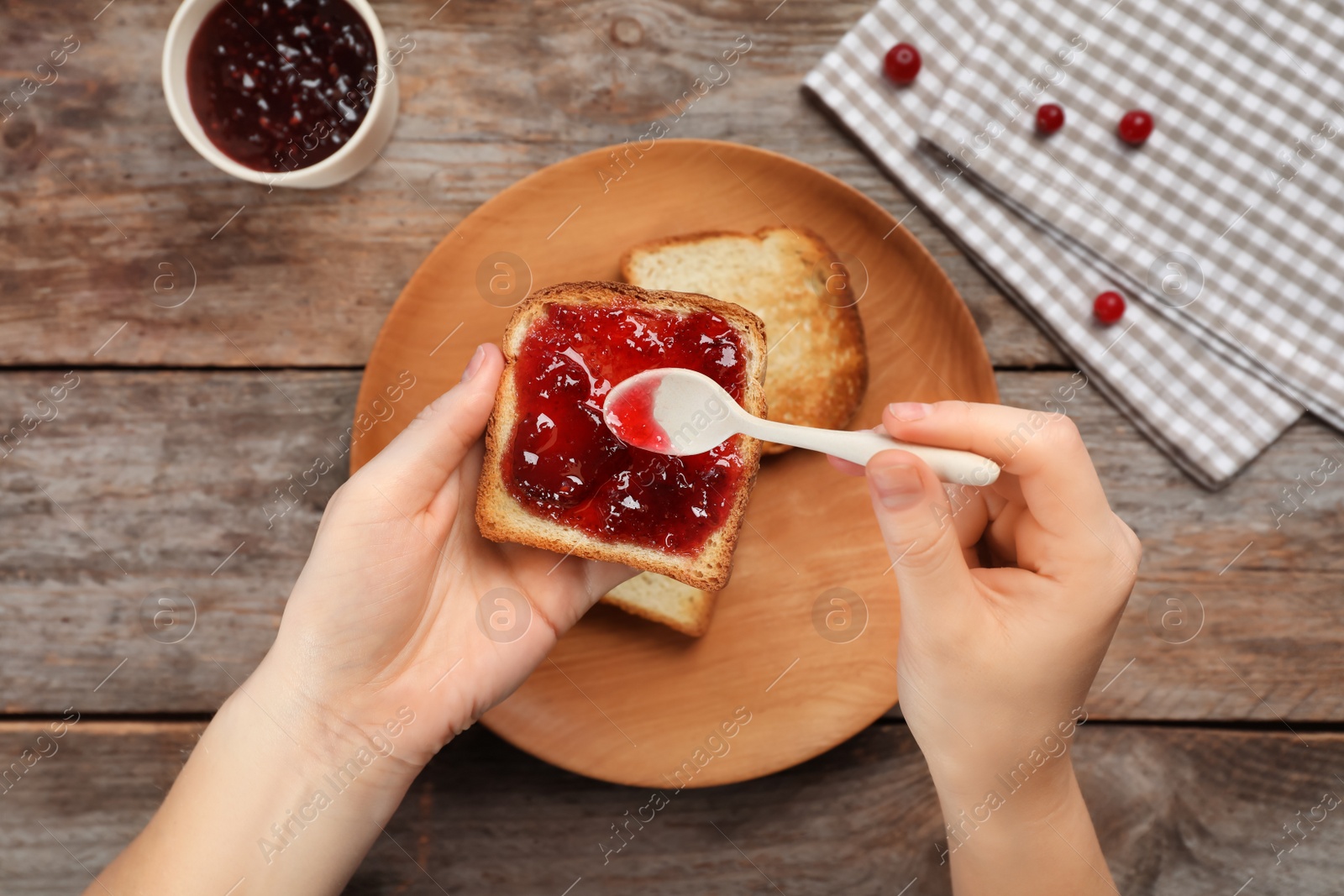 Photo of Woman spreading sweet jam on toast over table, top view