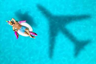 Shadow of airplane and happy man on inflatable ring in swimming pool, top view. Summer vacation