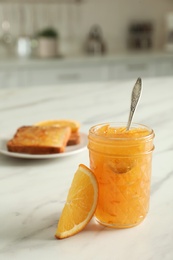 Photo of Delicious orange marmalade and citrus fruit slice on white marble table