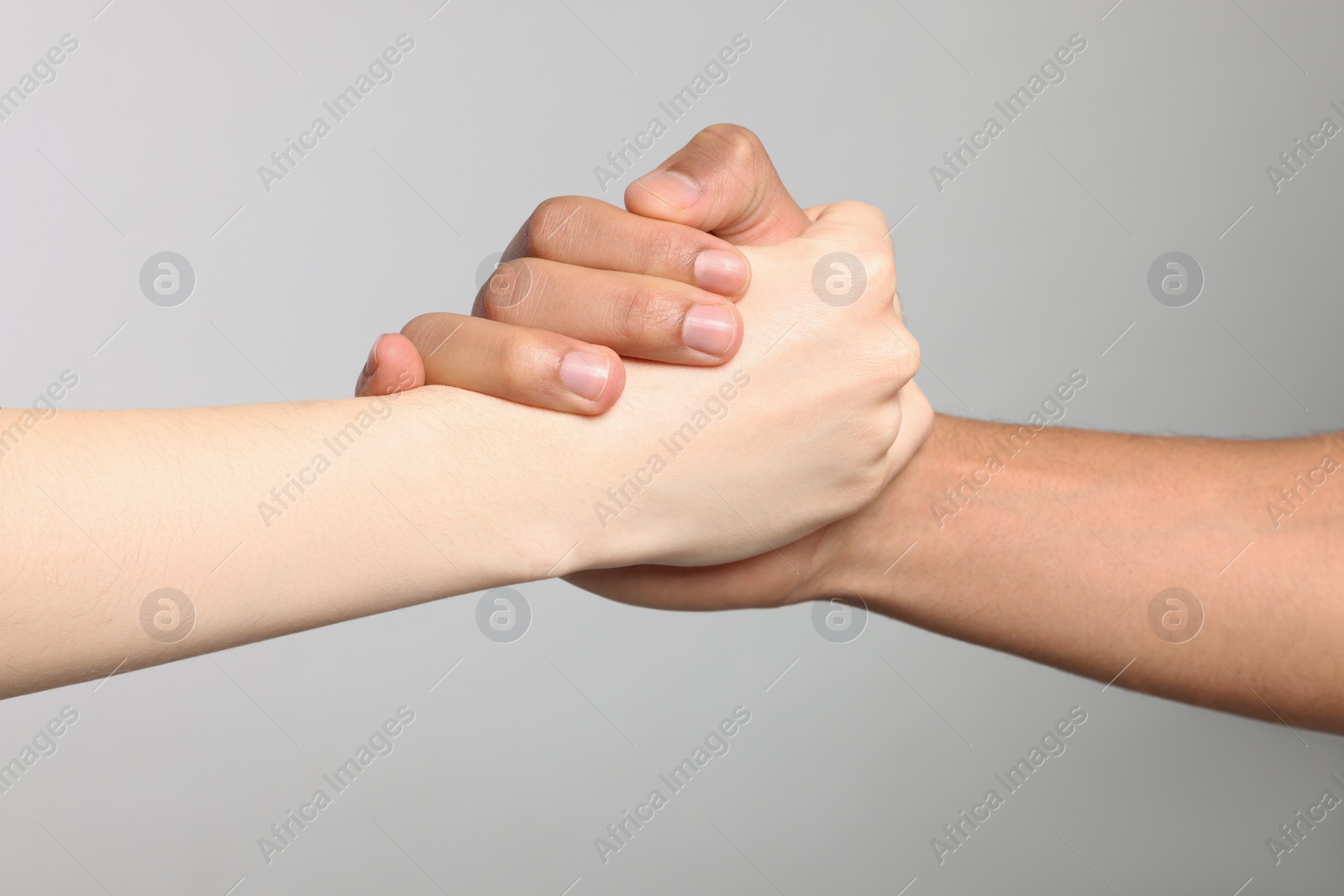 Photo of International relationships. People clasping hands on light grey background, closeup