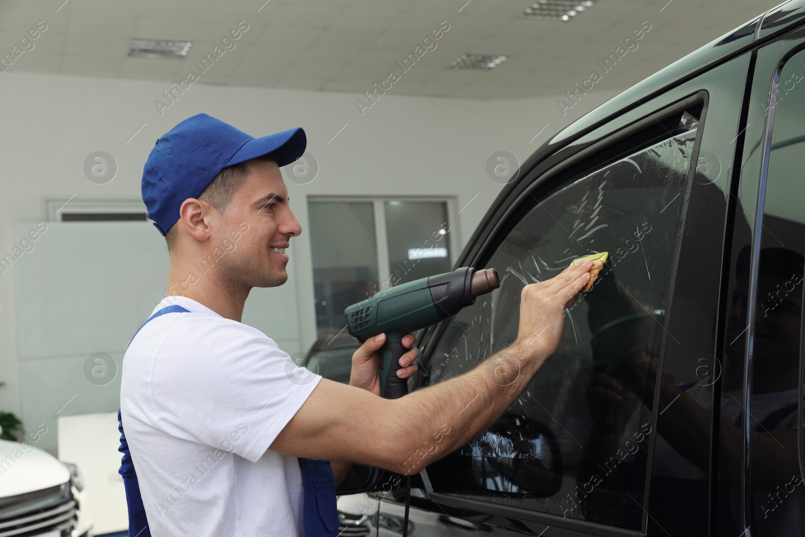 Photo of Worker tinting car window with foil in workshop