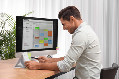 Handsome man using calendar app on computer in office