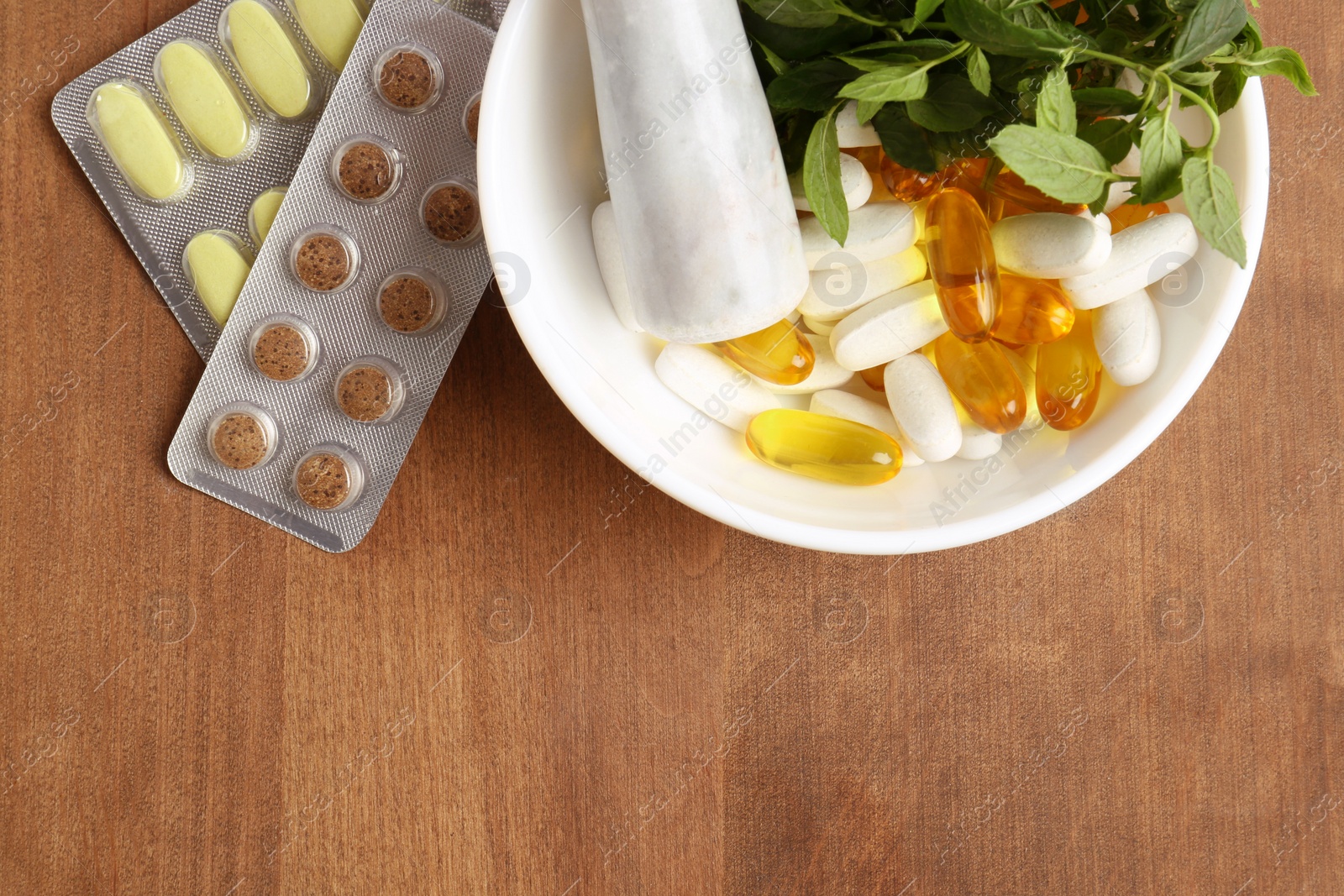 Photo of Mortar with fresh mint and pills on wooden table