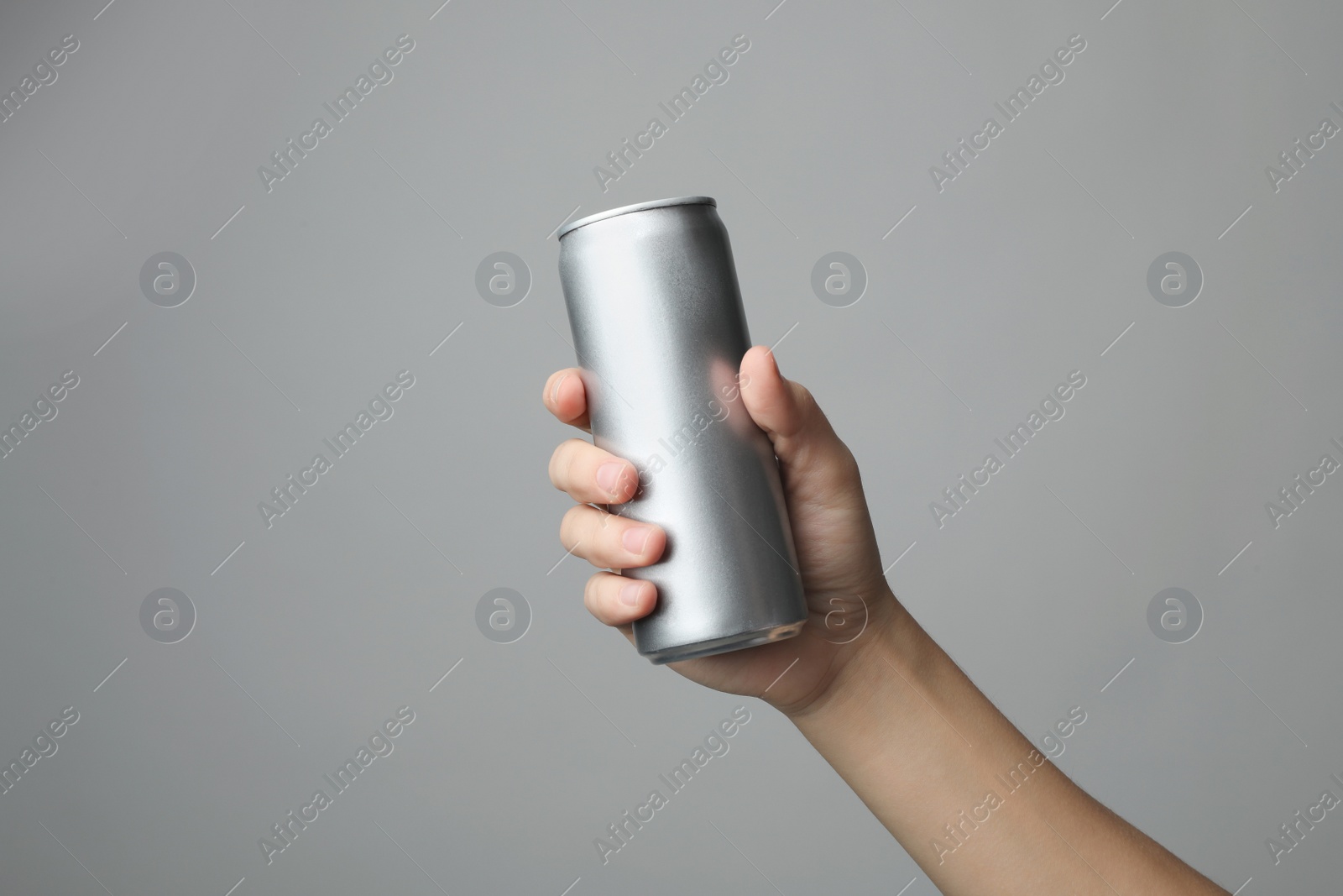 Photo of Woman holding aluminum can with beverage on grey background, closeup. Space for design