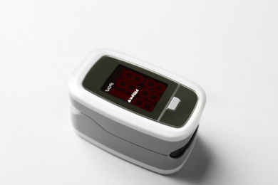 Photo of Modern fingertip pulse oximeter on white background, closeup