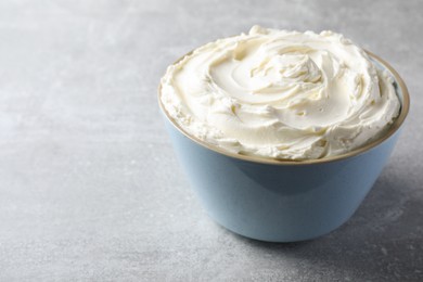 Photo of Bowl of tasty cream cheese on light grey table, space for text