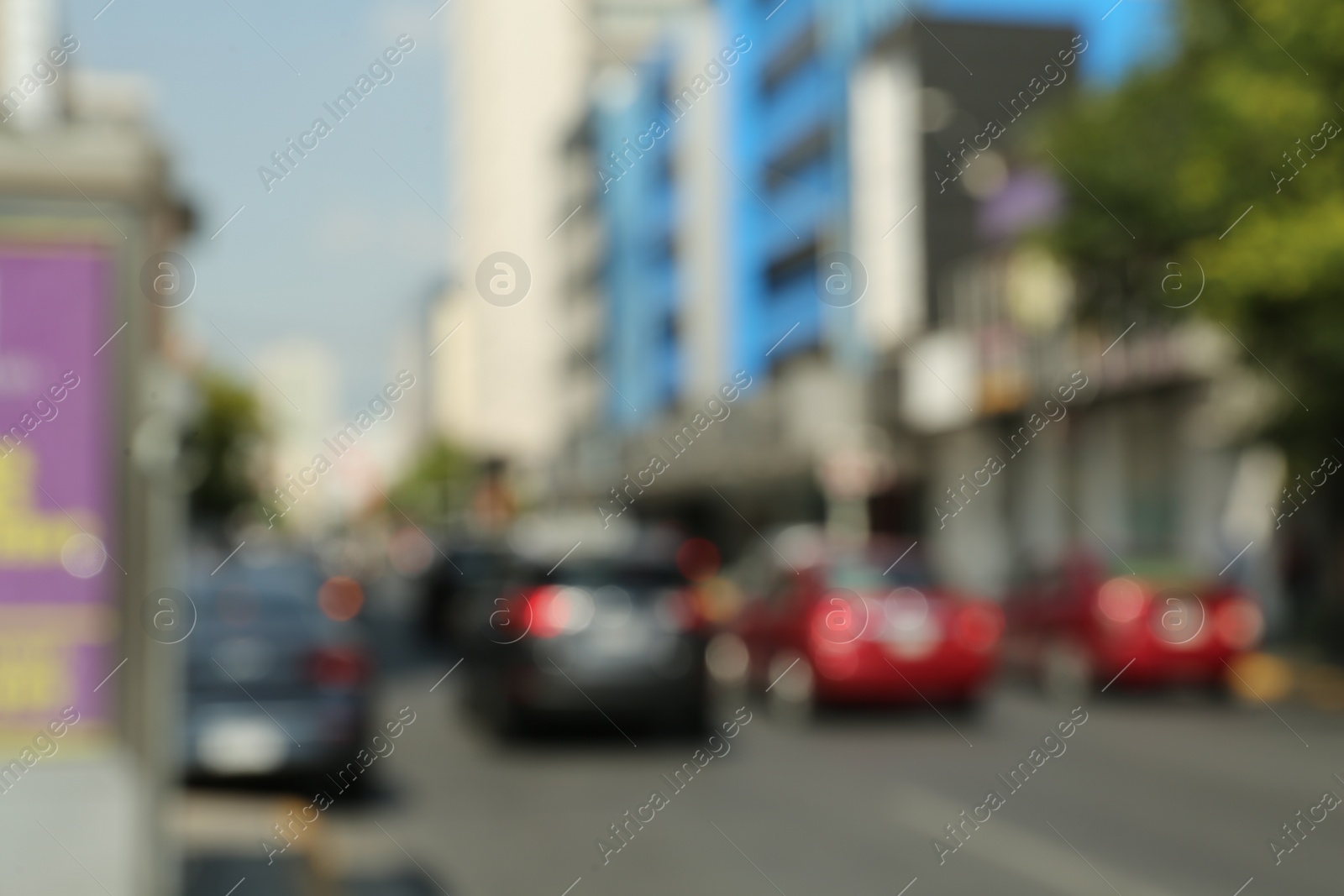 Photo of Blurred view of city street with buildings and parked cars