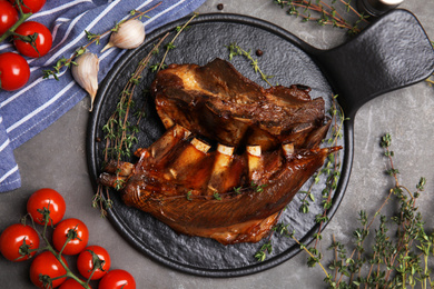 Photo of Delicious roasted ribs served on grey table, flat lay