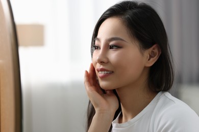 Photo of Woman with perfect skin looking at mirror indoors