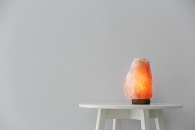 Himalayan salt lamp on table against white background. Space for text