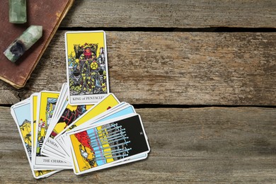 Tarot cards, crystals and old book on wooden table, flat lay. Space for text