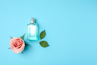 Bottle of perfume and rose on color background, top view