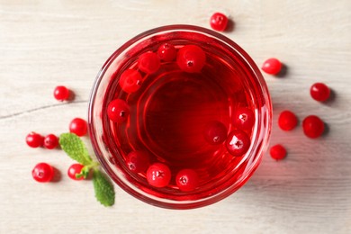 Photo of Tasty refreshing cranberry juice, mint and fresh berries on light wooden table, top view