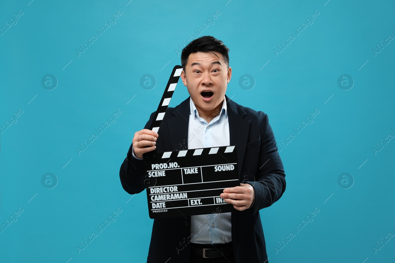 Photo of Emotional asian actor with clapperboard on light blue background. Film industry