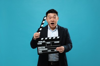 Photo of Emotional asian actor with clapperboard on light blue background. Film industry
