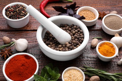 Photo of Mortar and different spices on wooden table, above view