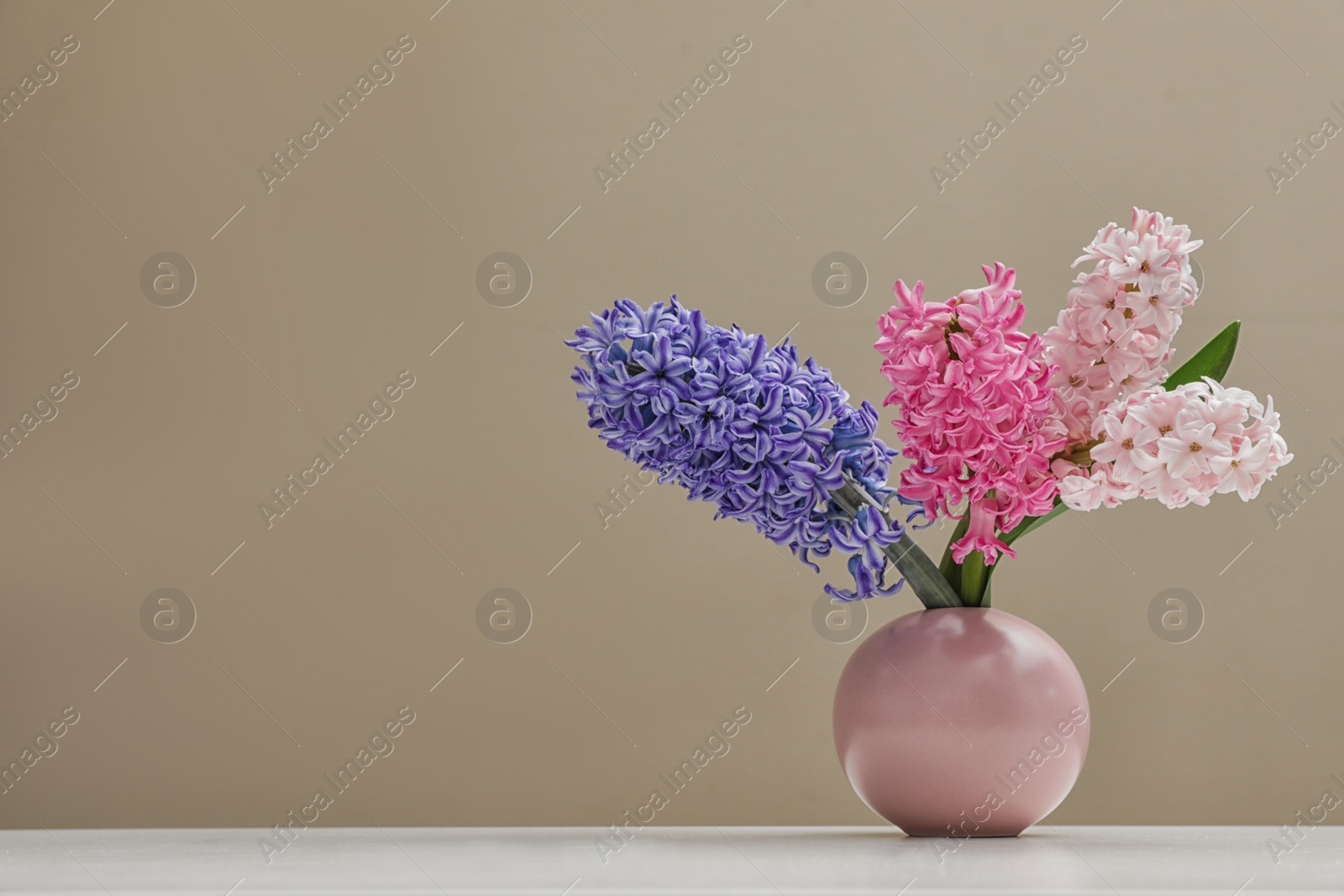 Photo of Beautiful hyacinths in vase on table against color background, space for text. Spring flowers