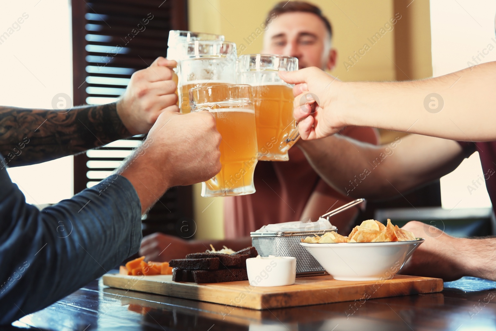 Photo of Friends clinking glasses with beer in pub