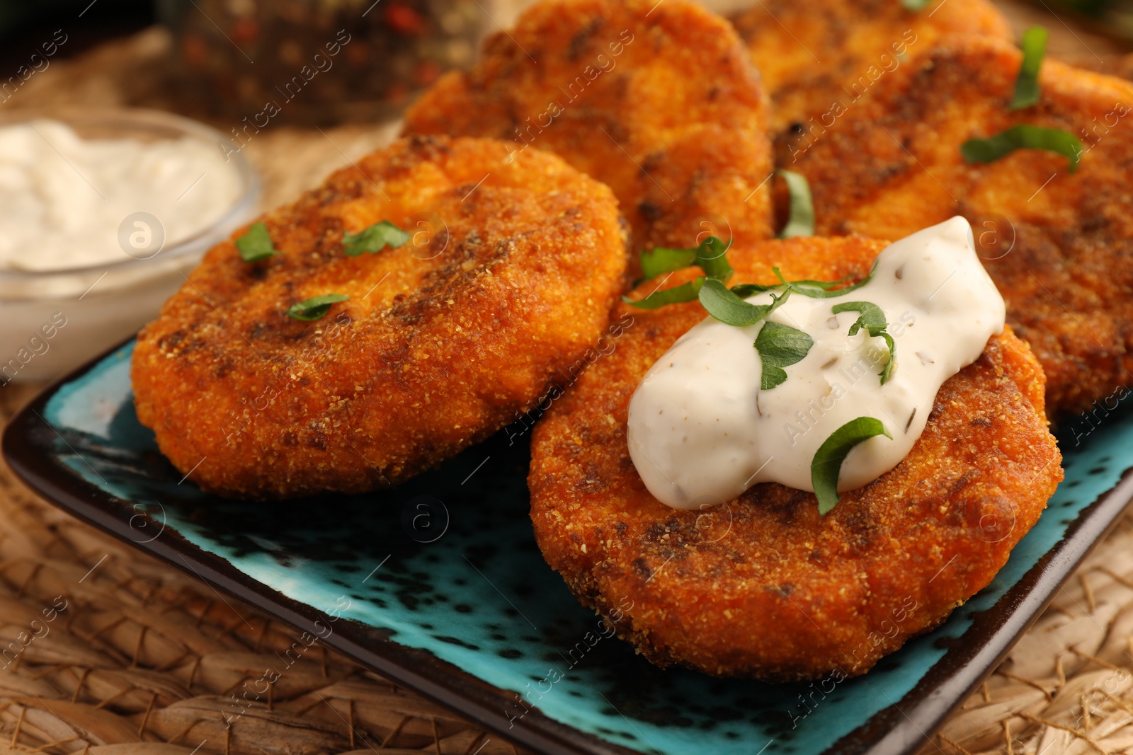 Photo of Tasty vegan cutlets with sauce on wicker mat, closeup