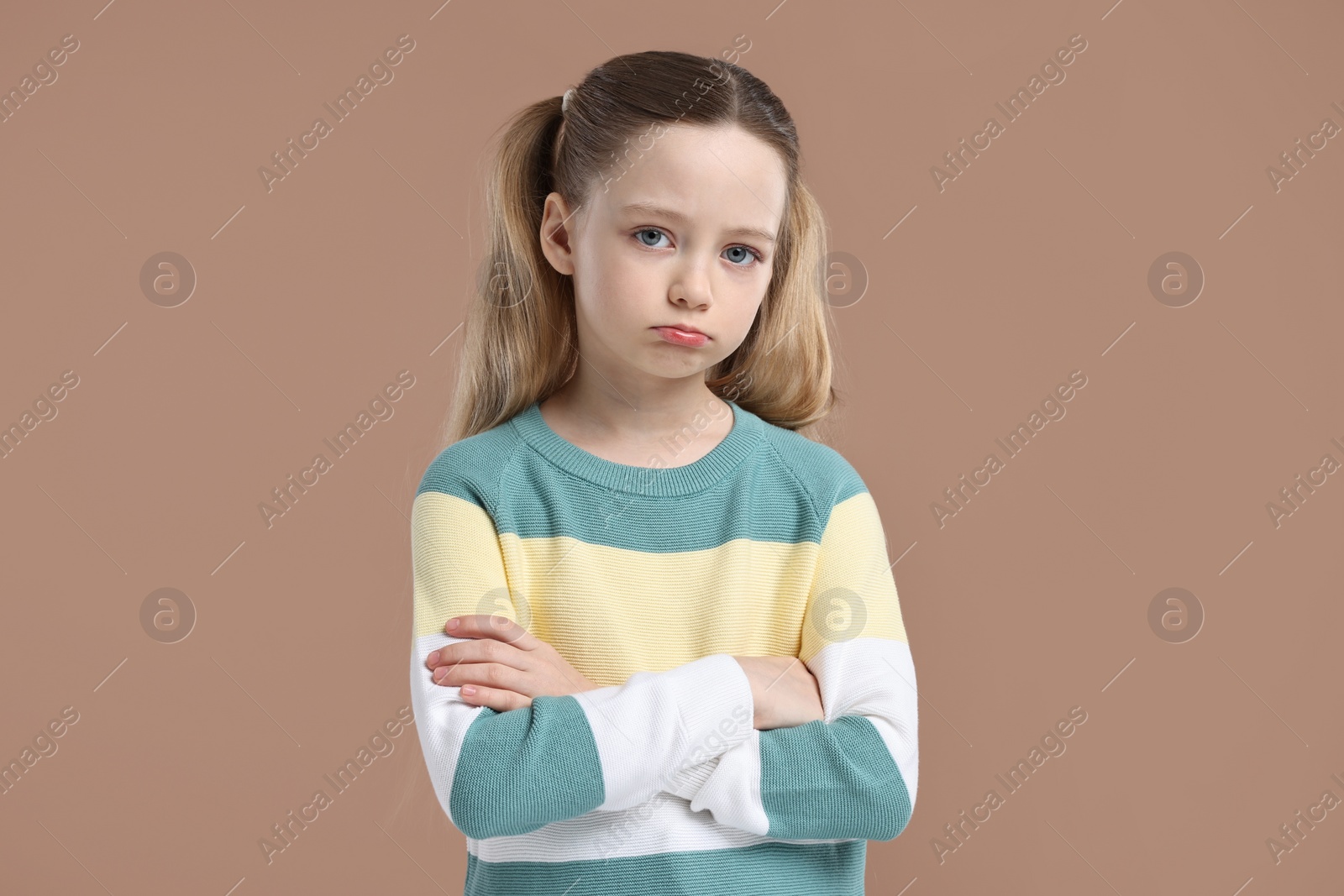 Photo of Portrait of sad girl with crossed arms on light brown background