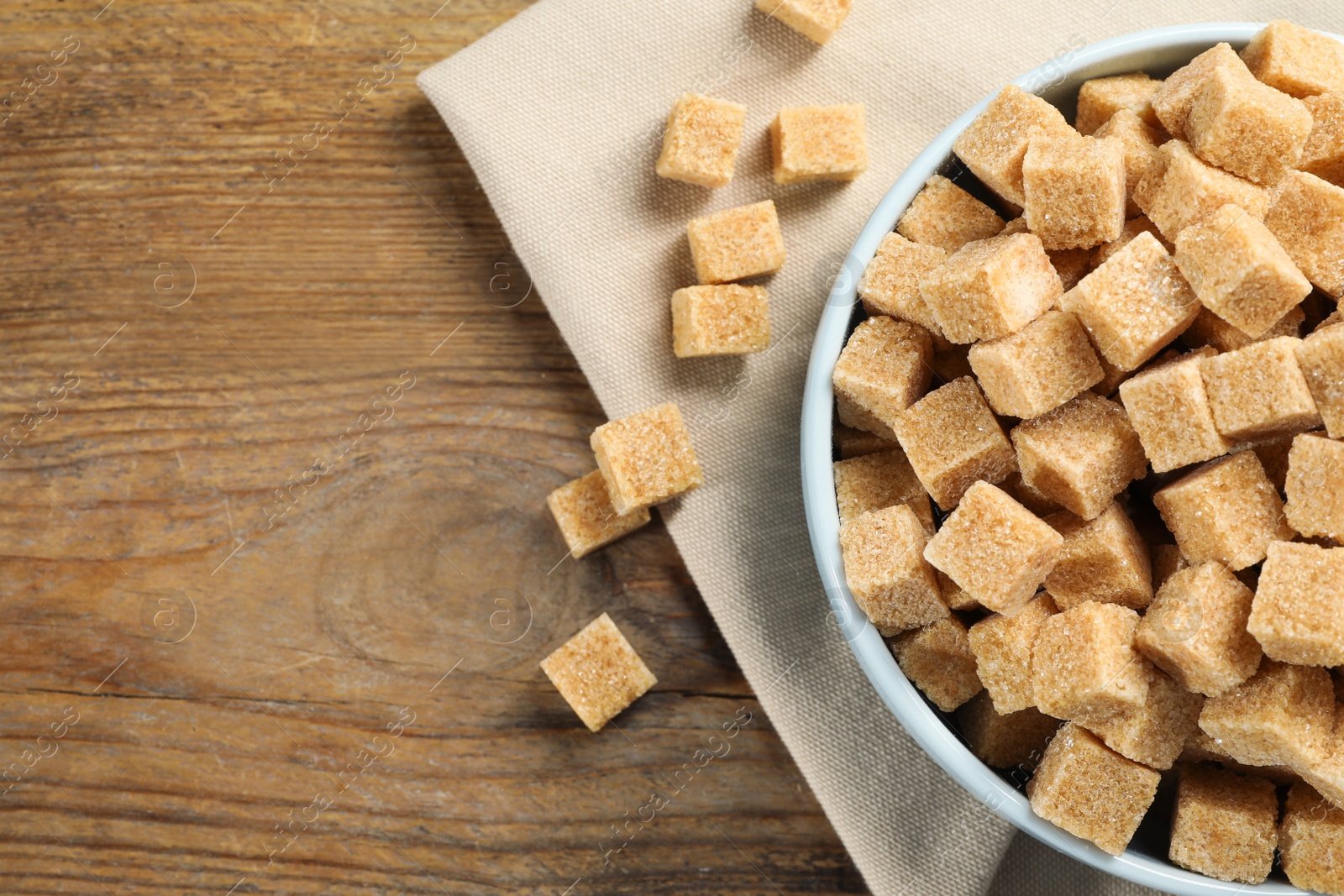 Photo of Brown sugar cubes on wooden table, flat lay. Space for text