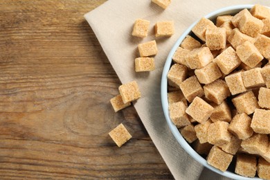 Brown sugar cubes on wooden table, flat lay. Space for text